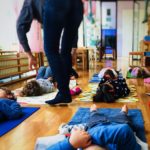 Bimbi sdraiati sui tappetini durante una lezione di yoga